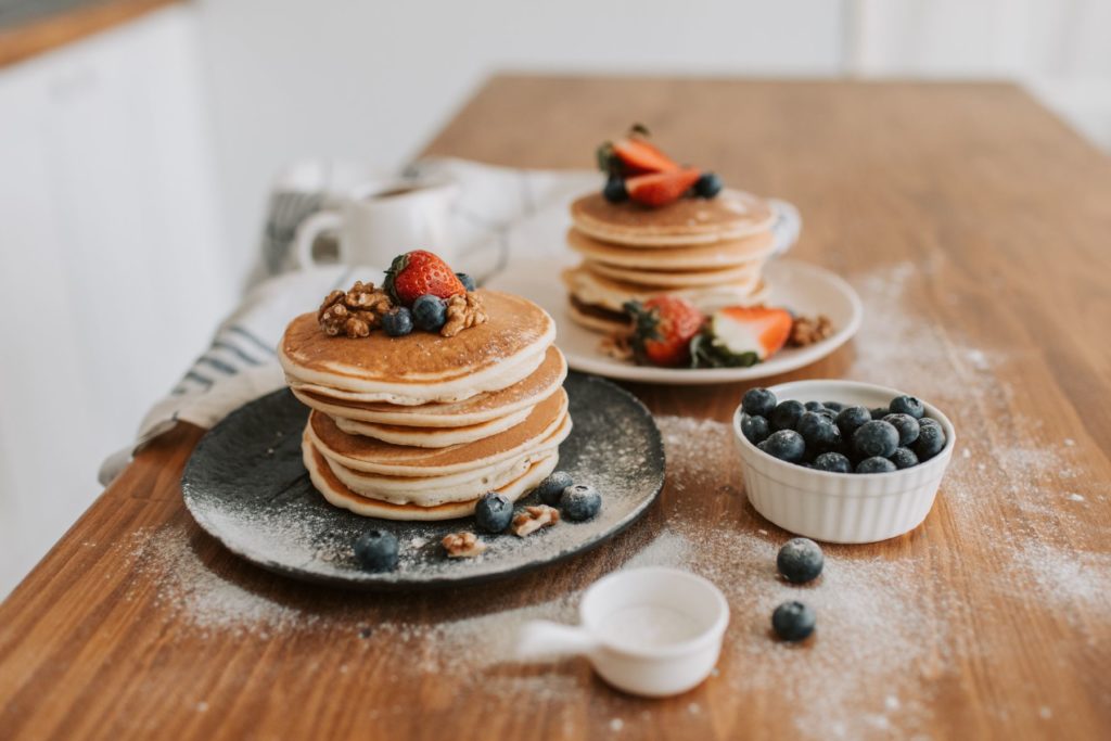 Stacks of Organic Cassava Flour pancakes topped with berries and walnuts. 